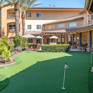 A courtyard with a putting green, surrounded by a building and palm trees.