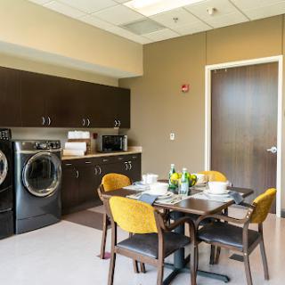 A contemporary kitchen and laundry area featuring a dining table with four chairs, modern appliances, and stylish decor.