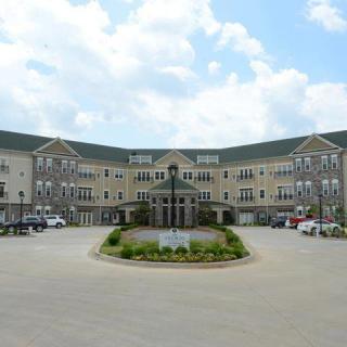 A large, elegant residential building with a circular driveway and landscaped entrance.