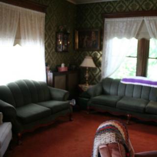 A vintage-style living room with green sofas, patterned wallpaper, and classic decor.