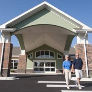 A couple standing in front of a large building entrance on a sunny day.