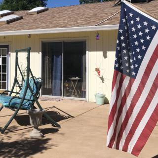 A sunny patio with a swing chair and an American flag.