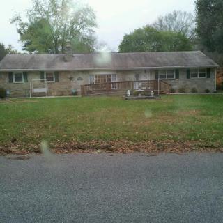 A peaceful suburban house with a well-maintained lawn and surrounding trees.