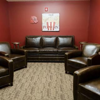 A comfortable waiting room with leather seating and red walls.