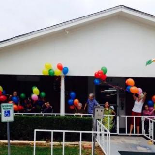 A group of people celebrating with colorful balloons on a porch.