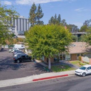 A small building with a parking lot surrounded by trees on a sunny day.