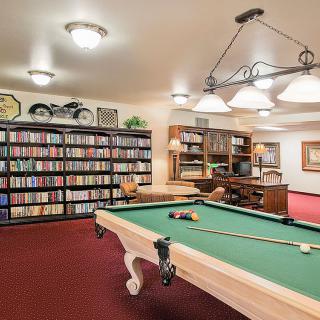 A cozy game room featuring a billiards table and a library with bookshelves.