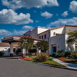 Modern medical facility with landscaped entrance under a bright sky.