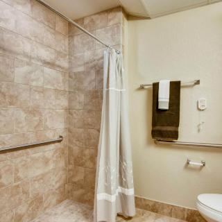 A neatly tiled bathroom with a shower area, curtain, mounted towels, and toilet.