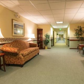 A well-lit hallway with a patterned sofa and various pieces of furniture.