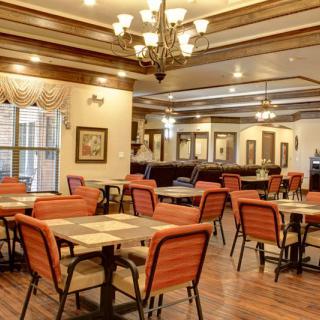 A cozy restaurant dining area with elegant chandeliers and wooden flooring.