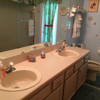 A bathroom with a double sink vanity, large mirror, and shower area.