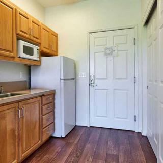 A small kitchen with wooden cabinets, a microwave, and a refrigerator.
