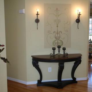 Elegantly decorated hallway with a console table, wall sconces, and candles.