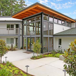 A modern building with a glass facade and landscaped entrance.