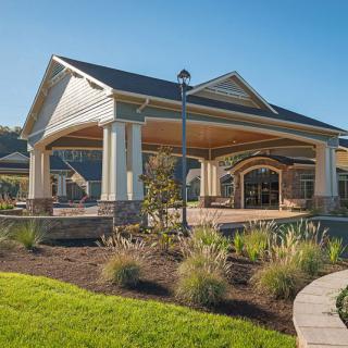 A modern building with a large roof and landscaped surroundings on a sunny day.