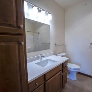 A clean and simple bathroom featuring a modern sink, wooden cabinetry, and a well-lit mirror.