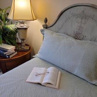 A cozy bedroom with a book open on the bed and a lamp illuminating the room.