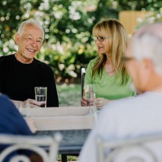 A group of people enjoying a conversation in a garden setting while having drinks.