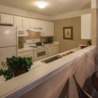 A cozy kitchen with white cabinetry and modern appliances, featuring an adjacent dining area.