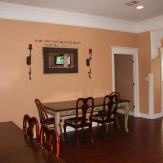A cozy dining room with a wooden table and chairs, complemented by wall decor and warm lighting.