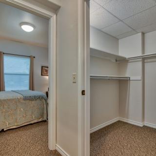 A view of a bedroom and an adjacent walk-in closet in a residential setting.