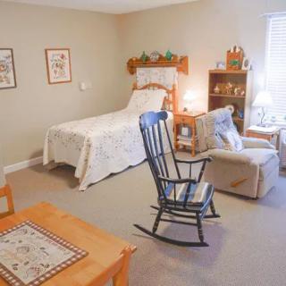 A cozy bedroom with a single bed, rocking chair, and warm lighting.