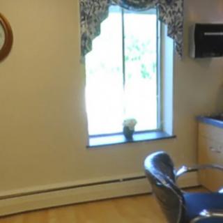 A cozy room with a window, chair and mirror.