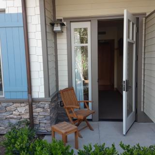 A cozy porch with a wooden chair and an open door leading into the house.