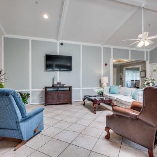 A spacious living room featuring comfortable seating, a wall-mounted television, and a ceiling fan.