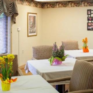 A cozy dining area with tables adorned with flower arrangements.
