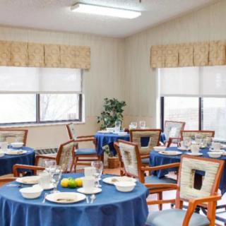 A neatly arranged dining room with tables covered in blue tablecloths and set for a meal.