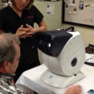 A person undergoing an eye examination using specialized optometry equipment.