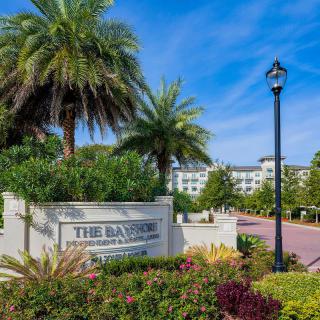 A well-landscaped residential area with palm trees and a sign displaying 'The Saxony.'