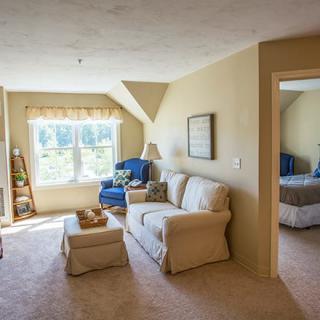 A cozy living room with a soft sofa and armchair bathed in natural sunlight.
