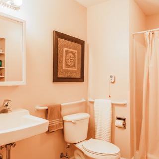 A cozy bathroom featuring a sink, toilet, and shower with warm lighting and decorative wall art.