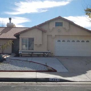 A single-story suburban house with a driveway and garage under a clear blue sky.