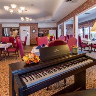 A cozy dining room with a digital piano and elegant red chairs.