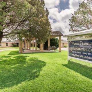 A well-maintained building with a sign surrounded by lush greenery and trees under a cloudy sky.