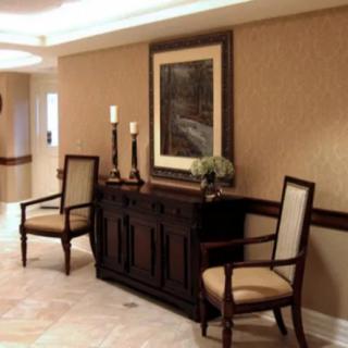 A well-decorated hallway with a console table, two chairs, artwork on the wall, and candles.