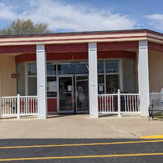 A welcoming front view of a single-story commercial building with red accents and outdoor seating.