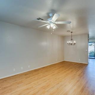 A modern living room with wood flooring and a ceiling fan.