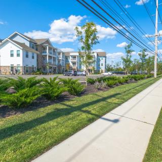 A modern apartment complex with landscaped surroundings and a clear blue sky.