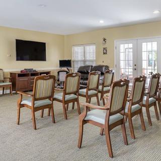 A well-arranged meeting room with rows of chairs facing a large television on the wall.