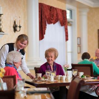 A warm dining experience at a senior care facility, where residents enjoy a meal together with attentive staff.