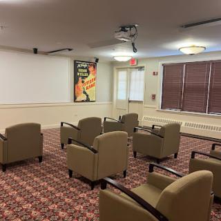 A meeting room setup with comfortable seating, a projector, and decorative wall art.