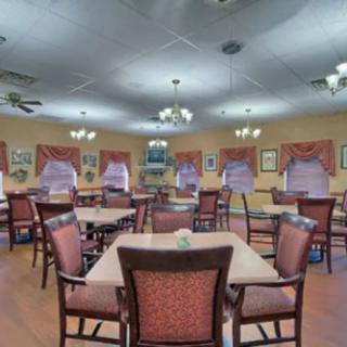 A spacious dining area with neatly arranged tables and chairs, adorned with elegant chandeliers and curtains.