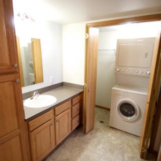 A spacious bathroom featuring a laundry area, complete with a vanity, sink, and washing machine.