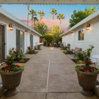 A serene courtyard with potted plants and palm trees visible against a sunset sky.