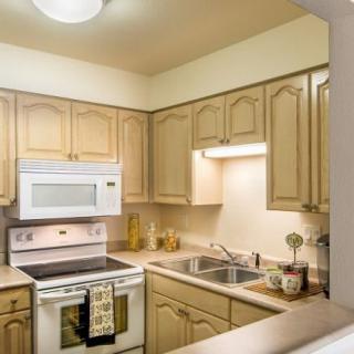 A cozy kitchen with wooden cabinets, featuring a microwave, oven, and sink.